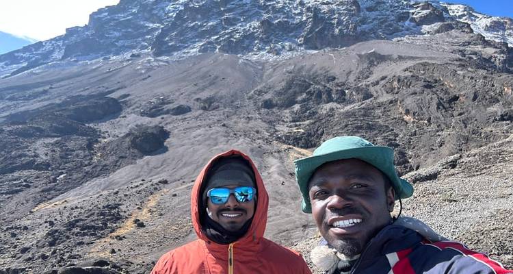 Deux personnes souriantes devant un paysage de montagnes rocheuses.