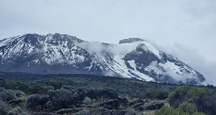 Pics montagneux enneigés sous un ciel nuageux.