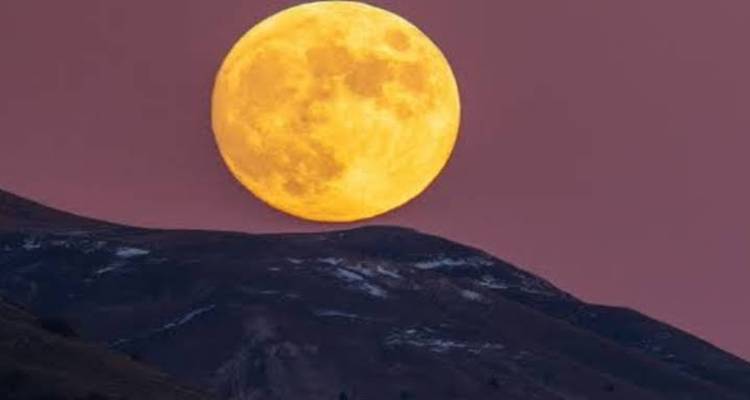 Une pleine lune au-dessus d'une crête de montagne.