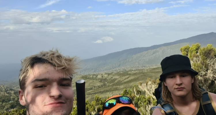 Groupe de personnes prenant un selfie avec des montagnes en arrière-plan.
