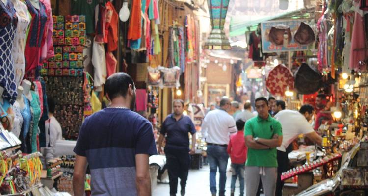 Ruelle étroite et animée du bazar Khan el-Khalili du Caire remplie de textiles colorés et de clients.