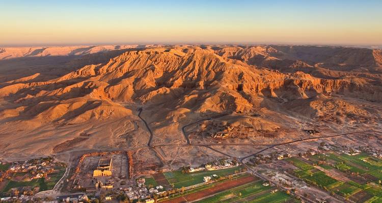Gouden-uur luchtfoto van ruige woestijngebergten en groene dorpjes aan de Nijloever in de buurt van Luxor.