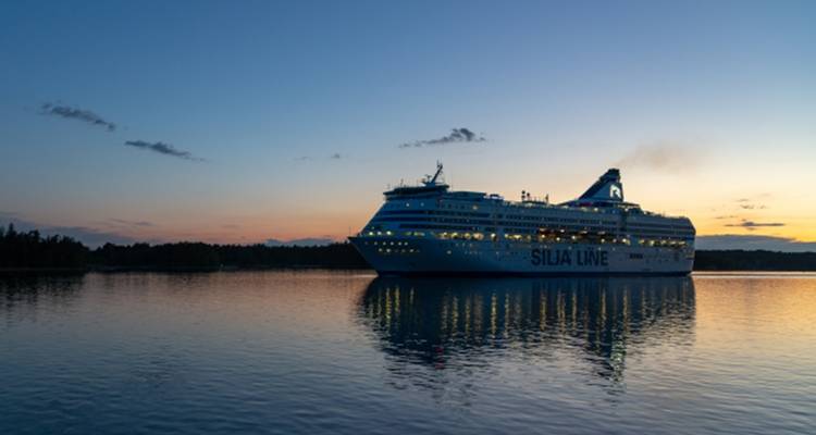 Un crucero navegando al atardecer con aguas tranquilas y un paisaje escénico de fondo.