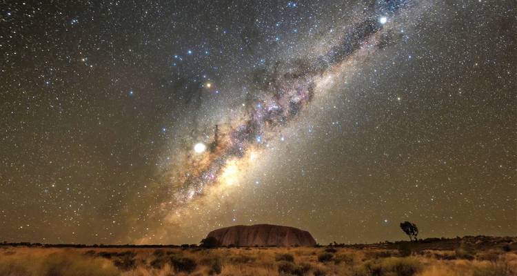 Atemberaubender Nachthimmel mit der Milchstraße, die sich über Uluru in der abgelegenen Wüstenlandschaft wölbt