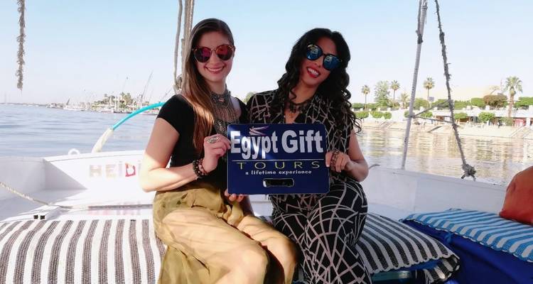 Zwei Frauen halten ein Schild für Egypt Gift Tours auf einem Boot.