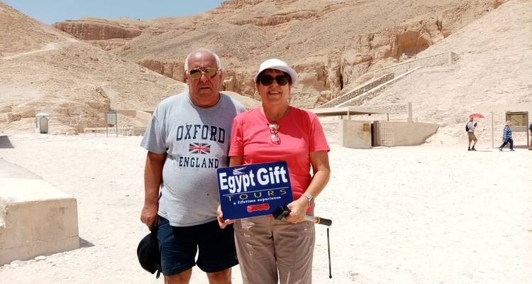 Dos personas sosteniendo un cartel de Egypt Gift Tours en un área desértica.