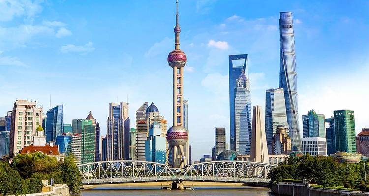 Skyline despejado de Shanghai durante el día con la Torre de la Perla Oriental y rascacielos futuristas sobre un puente de acero y el río.