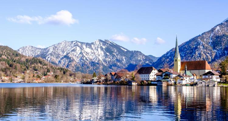 Ville pittoresque au bord d'un lac avec des montagnes en arrière-plan.