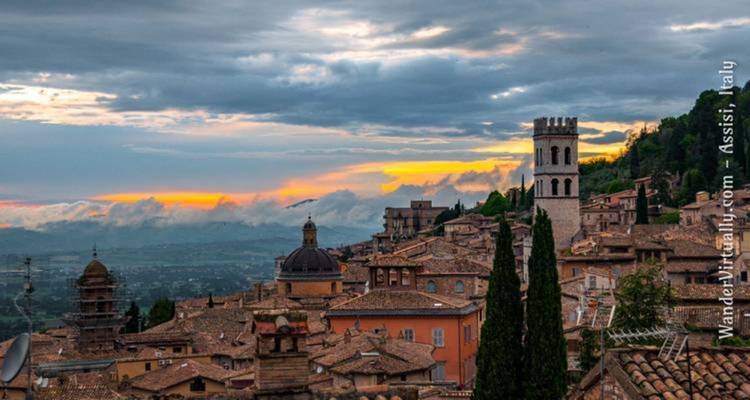 Scenic view over Assisi, Italy at sunset with a watermark.