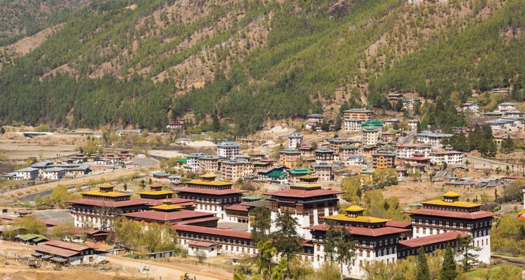 Vue aérienne d'une vallée bhoutanaise avec des bâtiments traditionnels.