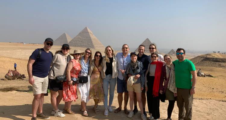 Gran grupo de turistas posa junto en frente del panorama de la pirámide en la meseta de Giza.