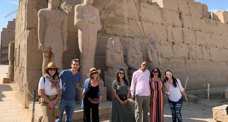 Groupe de touristes posant devant de grandes statues antiques.