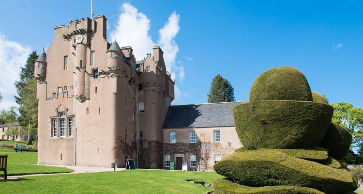 Château pittoresque encadré par des topiaires sculptées sous un ciel bleu éclatant