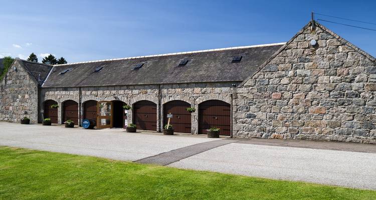 Bloc d'écurie en pierre avec portes en bois cintrées sur le domaine royal