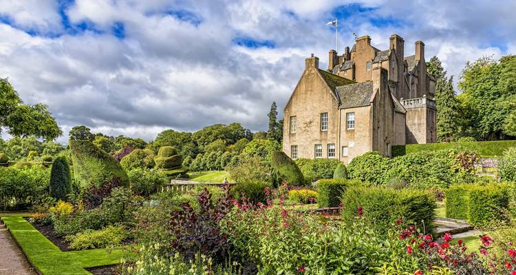 Château s'élevant au-dessus de jardins à la française luxuriants débordant de fleurs colorées