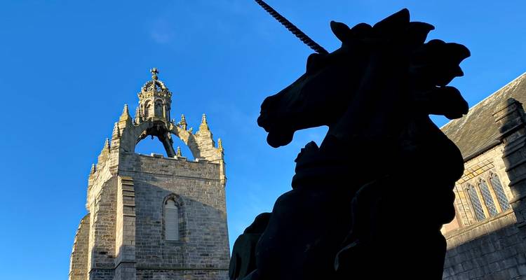 Silhouette d'une statue de licorne avec un clocher d'église historique en arrière-plan