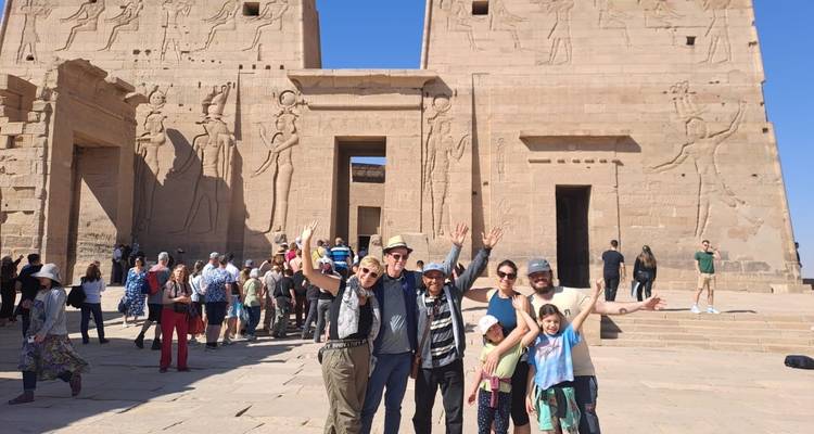 Des touristes posant devant un temple avec des hiéroglyphes.