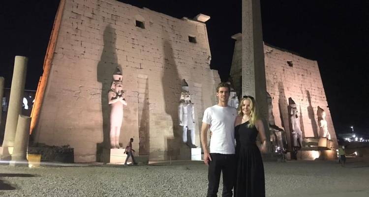 Stel poseert voor een verlichte oude tempel in de nacht.