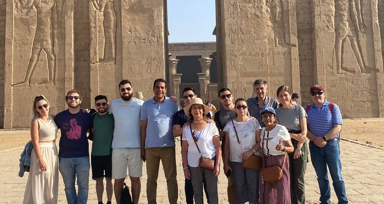 Grupo de turistas posando ante las ruinas de un antiguo templo.