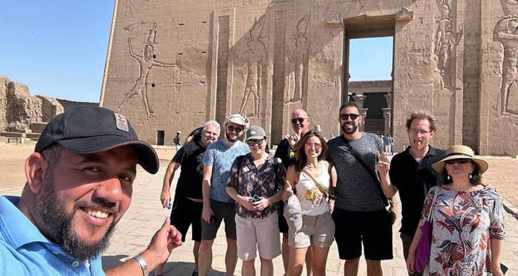 Toeristen die voor een oude zandstenen tempelgevel met gesneden reliëfs staan en samen een selfie maken.