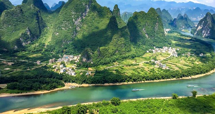 Vue aérienne de montagnes karstiques luxuriantes et d'une rivière.