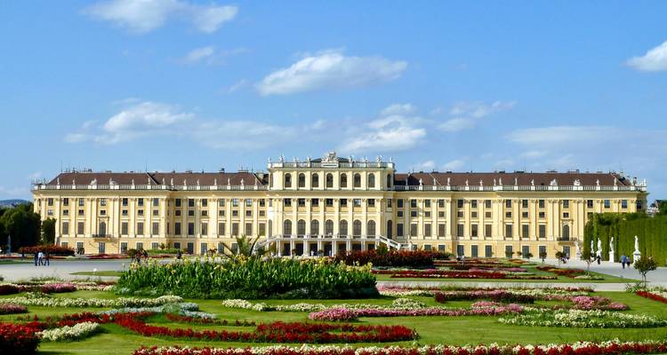 Baroque Schönbrunn Palace framed by manicured flower gardens under a clear Viennese sky.