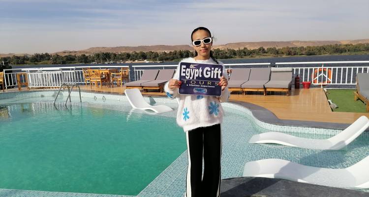 Une femme tenant une pancarte près d'une piscine sur un navire de croisière.