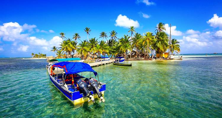 Île tropicale avec des palmiers et des bateaux dans une eau claire.