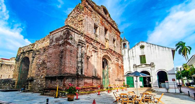 Bâtiment historique en brique avec des plantes et des chaises à l'extérieur.