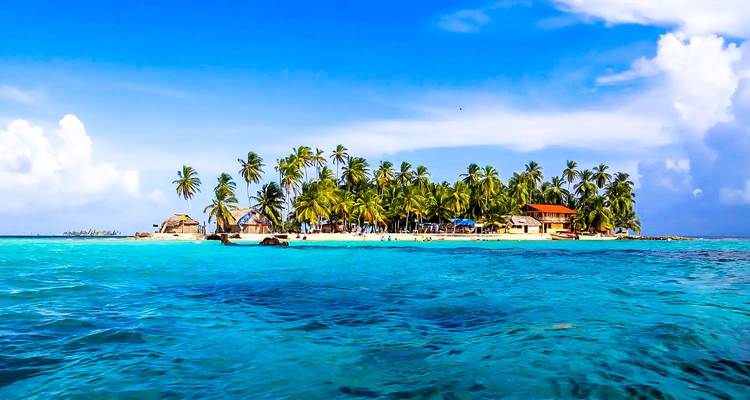 Isla tropical con palmeras rodeada de agua azul.