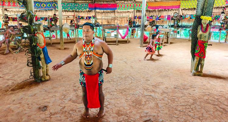 Hombre con atuendo tribal realizando danza tradicional en interiores.