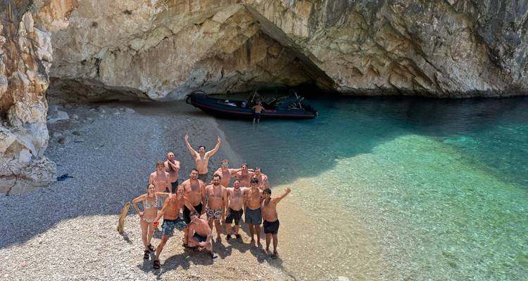 Groupe de personnes posant sur une plage près de l'entrée d'une grotte