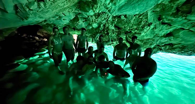 Groupe de personnes illuminées dans une grotte avec une lueur verte.