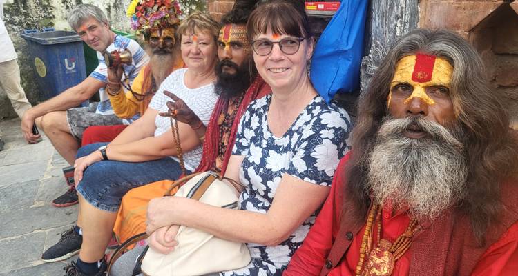 Group of people sitting with Sadhus in colorful attire.