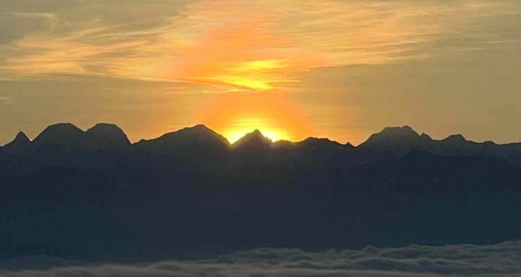 Sunset over mountain peaks with a clear sky.