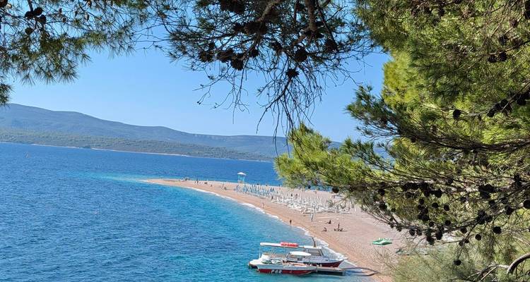 View of a pebble beach and a boat on blue water.