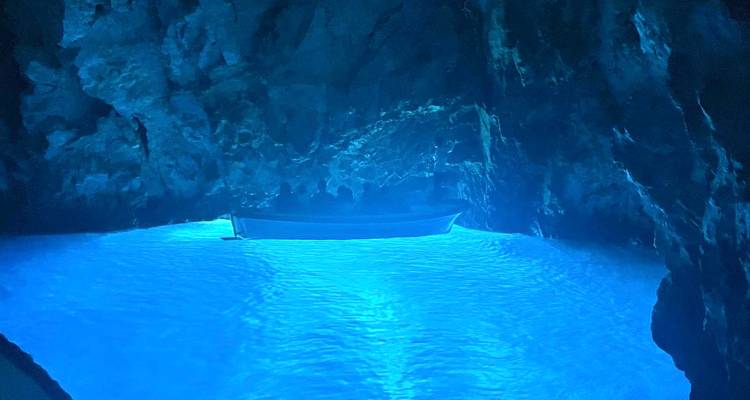 À l'intérieur d'une grotte bleue lumineuse avec un bateau reflété dans l'eau.