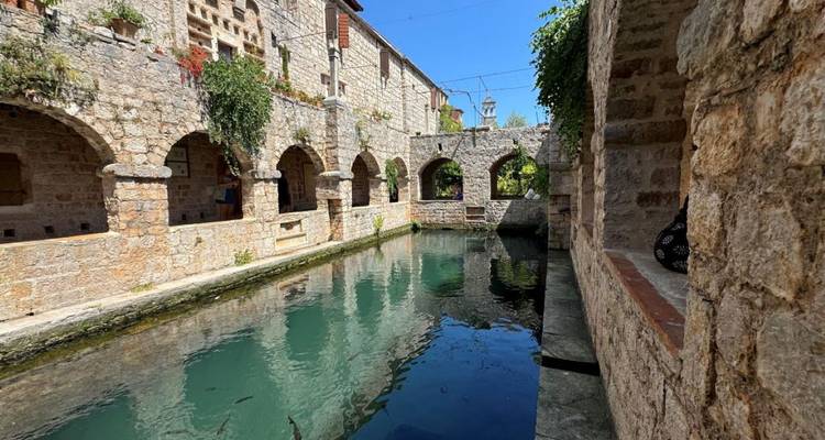 Bâtiments historiques en pierre avec des arches au-dessus d'un canal pittoresque.