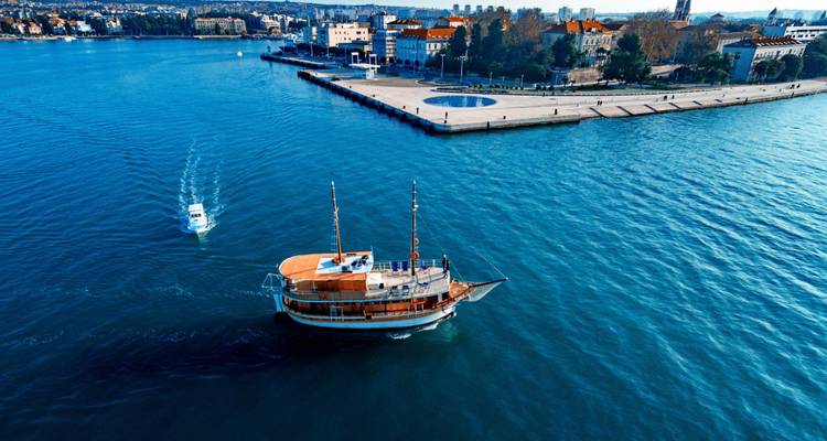 Boat departing from a coastal city with a waterfront promenade.