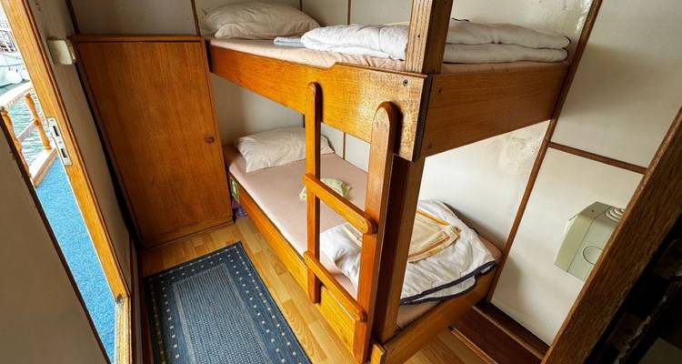 Small cabin room with bunk beds and wooden furnishings.