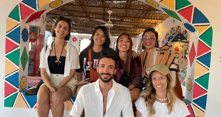 Eine Gruppe, die in einem warm dekorierten, bunten Torbogen sitzt.