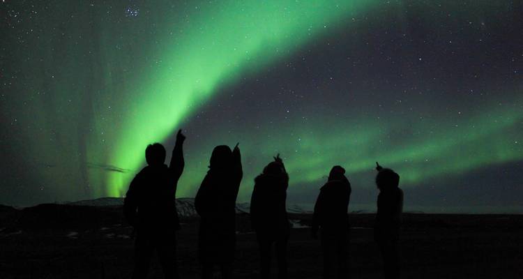 Silhouette of people under the Northern Lights.