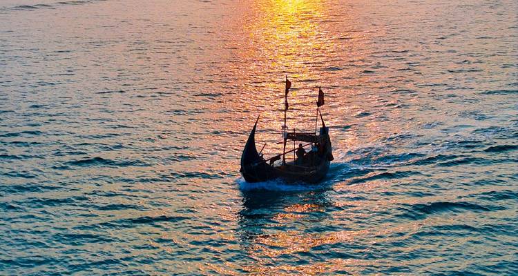 Silhouet van een boot tegen een zonsondergang op het water.