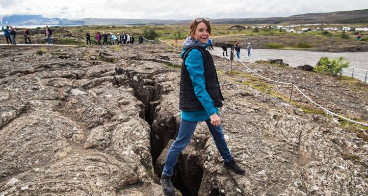 Frau balanciert über einen Riss im Thingvellir-Nationalpark.