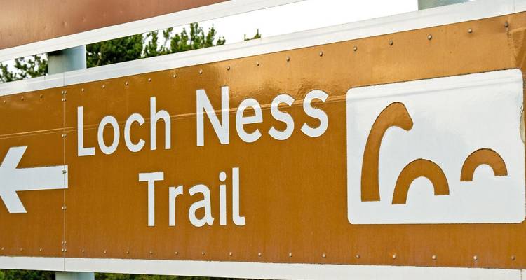 Wegweiser für den Loch Ness Trail in Braun und Weiß mit einem stilisierten Monstersymbol.