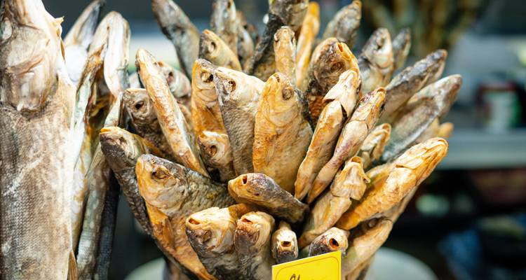 Pila de pescado ahumado o seco expuesto en un puesto de mercado báltico cubierto.