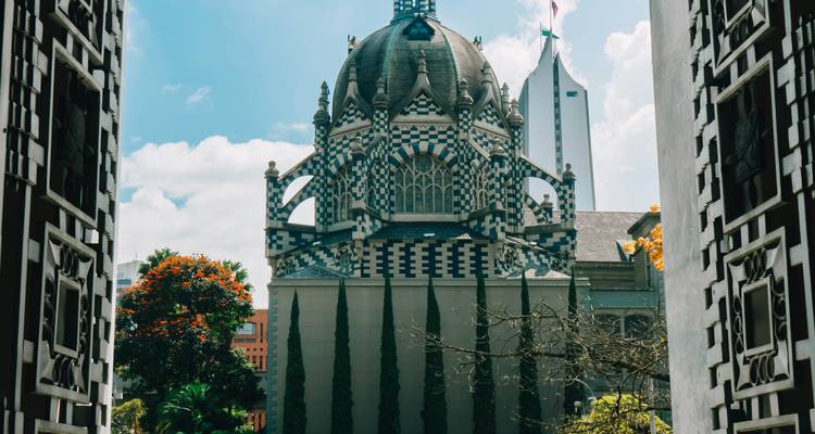 Edificio abovedado con patrón de tablero de ajedrez enmarcado por puertas de hierro ornamentadas en blanco y negro en un día brillante