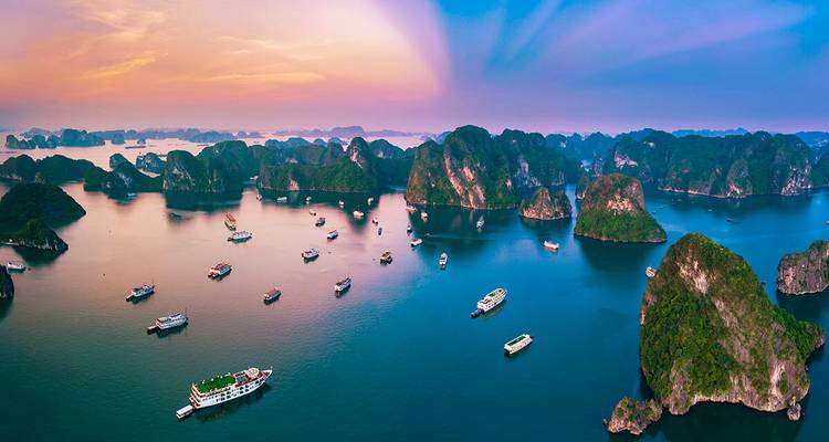 Vista panorámica de la Bahía de Halong al atardecer con numerosos barcos.