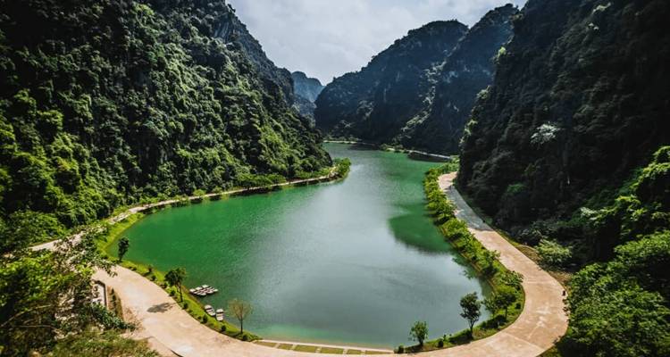 Serene landschap van een rivier die tussen weelderige, rotsachtige heuvels in Ninh Binh stroomt.