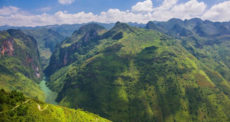 Weelderige groene vallei met een rivier die er doorheen stroomt.